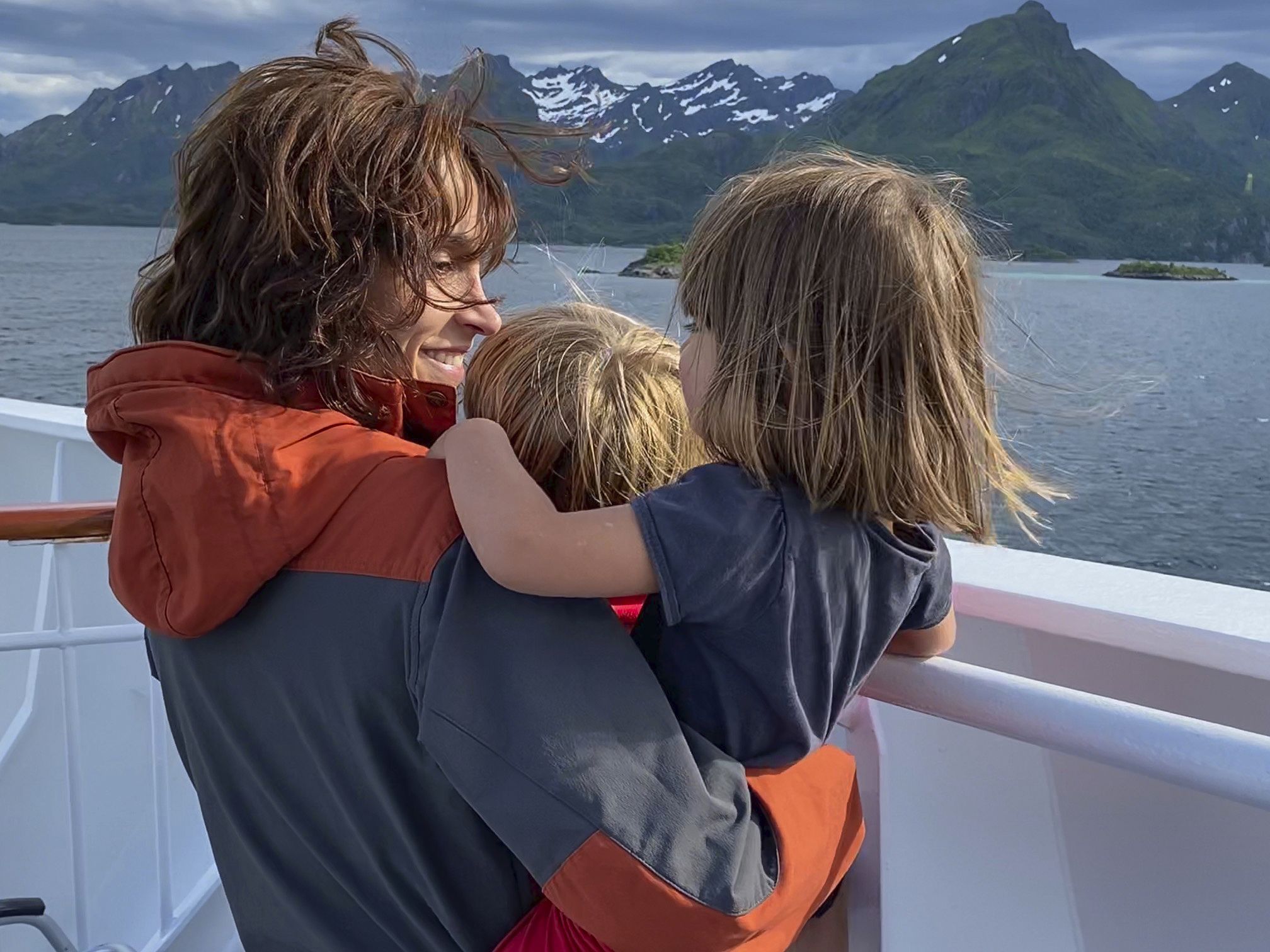 Woman holding two children looking out to sea