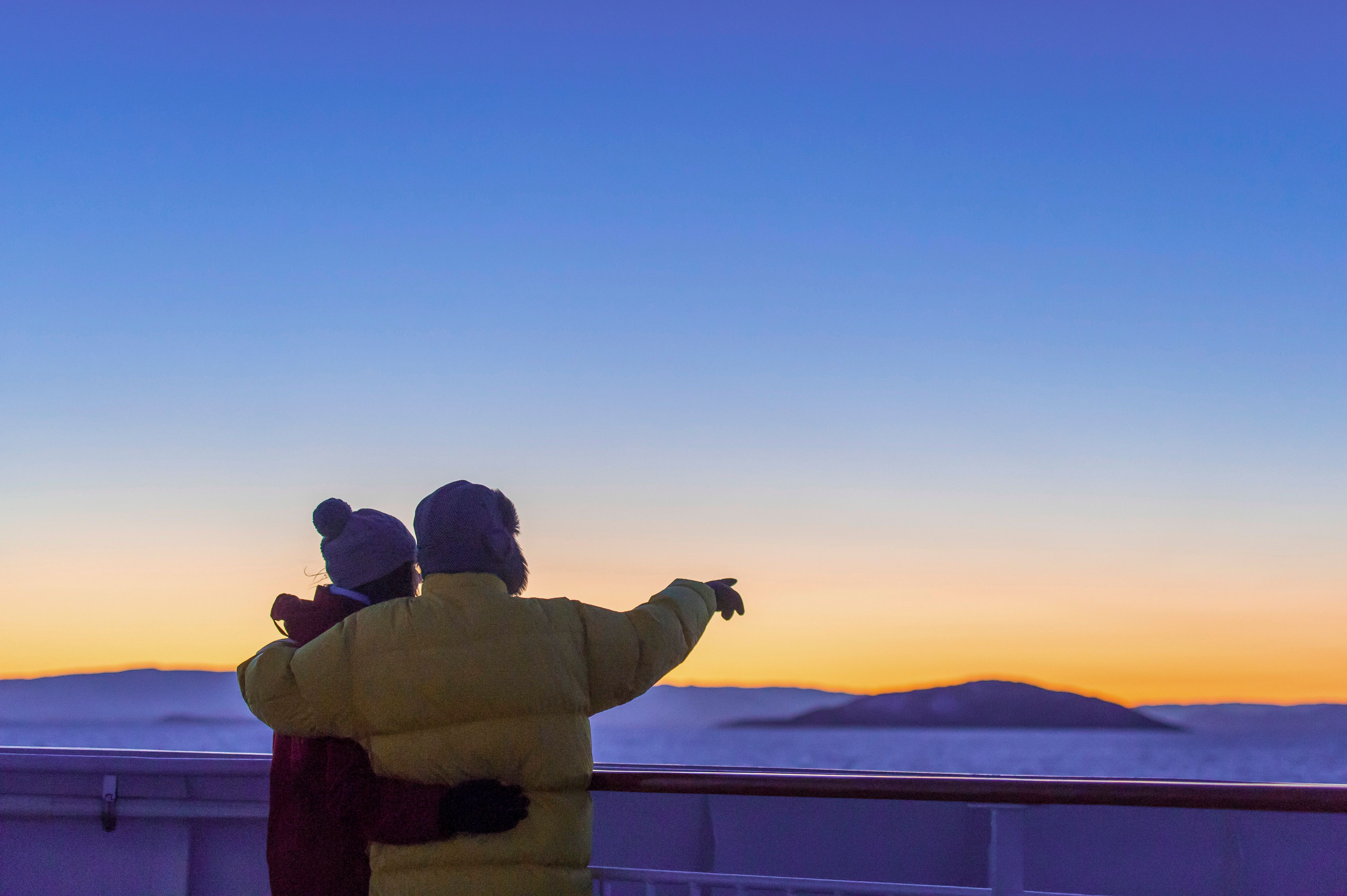 Two people looking out to colourful sky over Norway