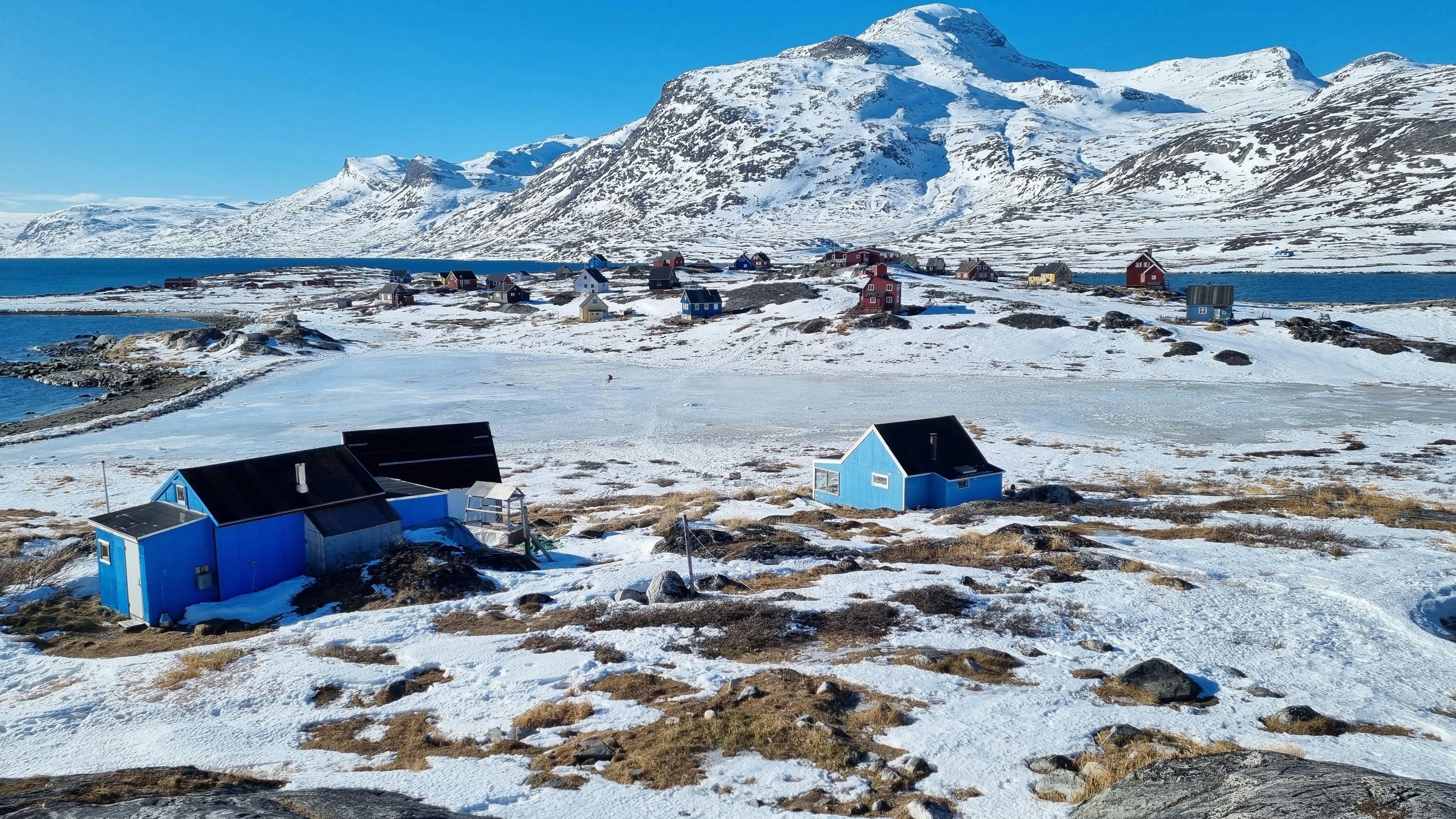 A group of small houses sitting on top of a snow covered field in Nuuk, Greenland